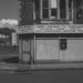 Black and white photo of a closed-down corner shop advertising used TVs.