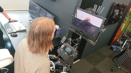 Camera operator uses remote control wheels while observing a radio-linked monitor.