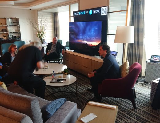 People sitting around a large, high-quality video display in a classy hotel suite.