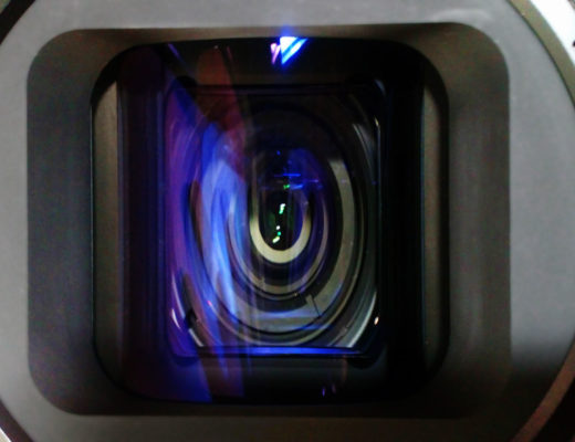 Front view of an anamorphic lens with the internal elements visibly distorted by the cylindrical front element.