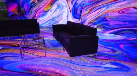 Two couches and a coffee table on a virtual production LED stage displaying an abstract pattern of coloured swirls