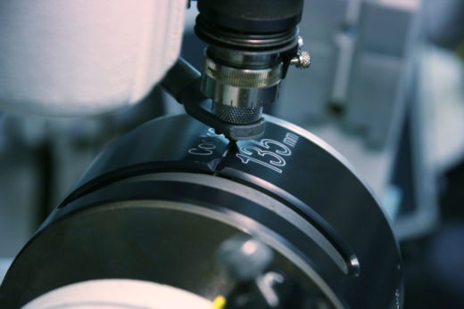 A Cooke lens being engraved with its focal length during manufacturing.