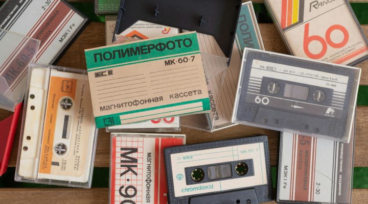 A pile of compact cassette tapes, some cased, some not, many with cyrillic lettering.