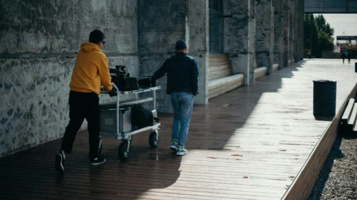 Better ways to control things 4 Two people pushing a Magliner equipment cart along a boardwalk by a shingle beach.