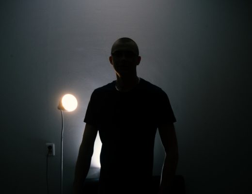Man in a T-shirt silhouetted against a light.