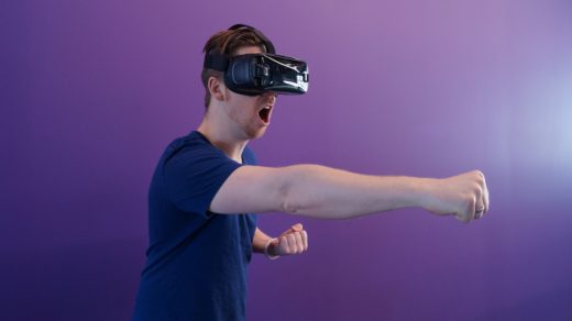 Man wearing virtual reality headset making punching motion.