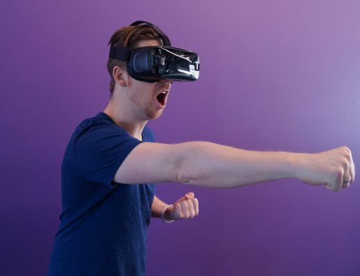 Man wearing virtual reality headset making punching motion.