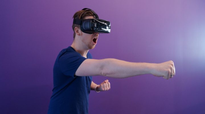 Man wearing virtual reality headset making punching motion.