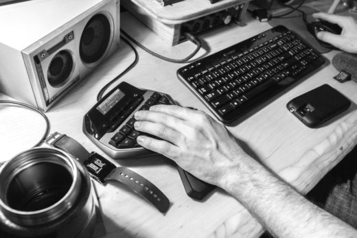 Monochrome image of a hand using a specialist extra keyboard on a computer.