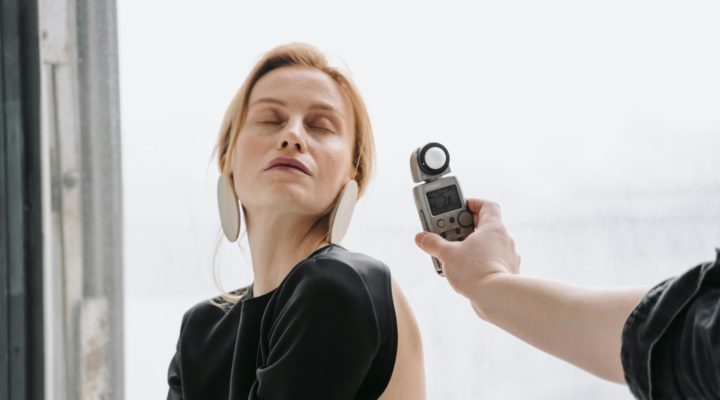 A hand holding a light meter near a woman's face .