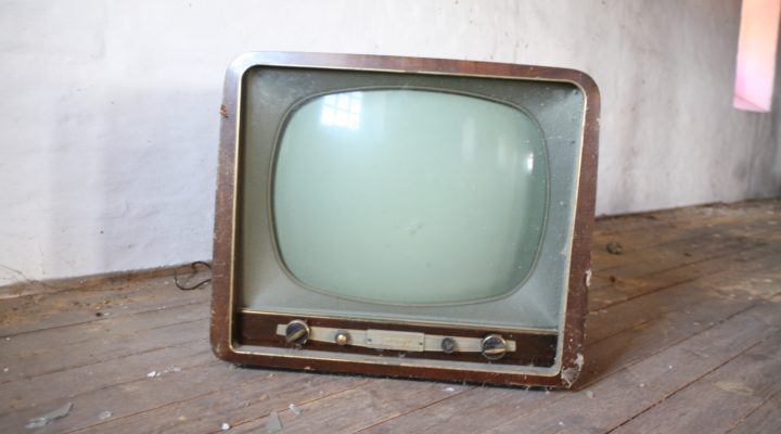 An old-style cathode ray tube TV, covered in spider webs.