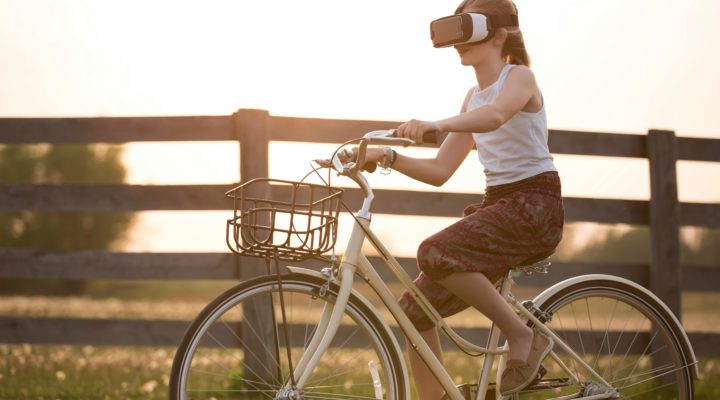 A woman on a bicycle wearing a virtual reality headset.